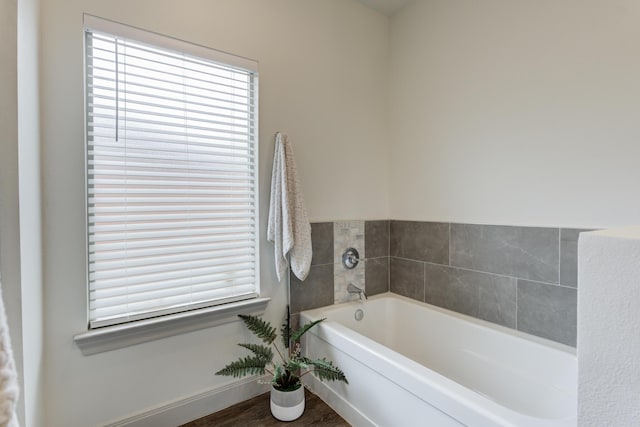full bath with baseboards, wood finished floors, and a garden tub