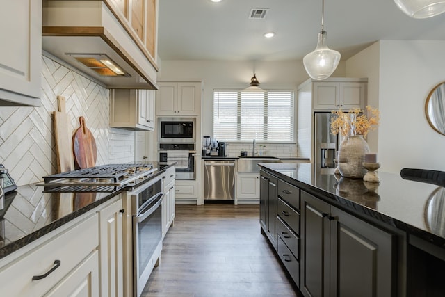 kitchen featuring a sink, decorative backsplash, visible vents, appliances with stainless steel finishes, and wood finished floors