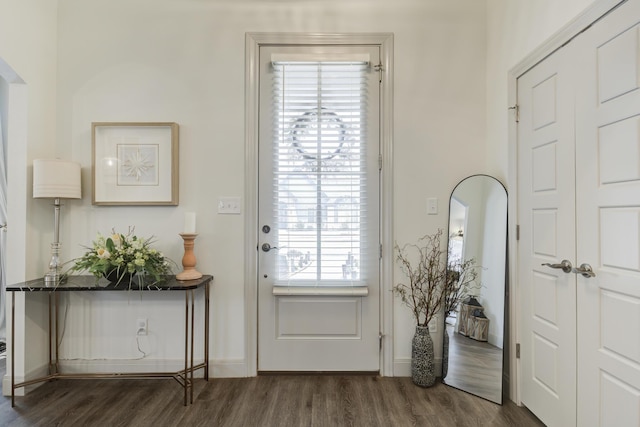 entryway featuring arched walkways, baseboards, and dark wood finished floors