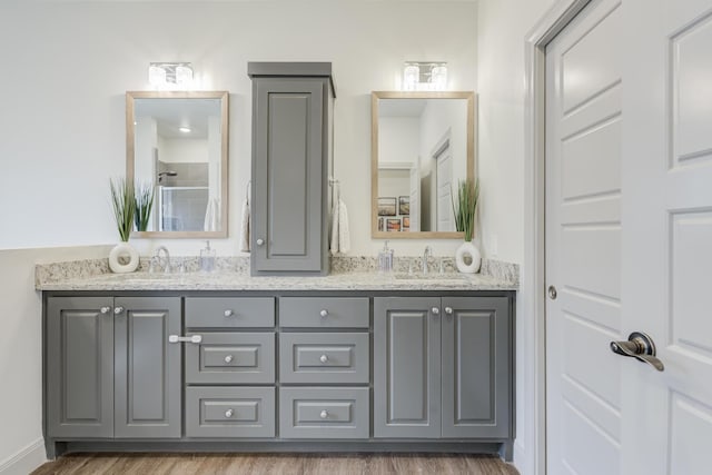 full bathroom with double vanity, wood finished floors, and a sink