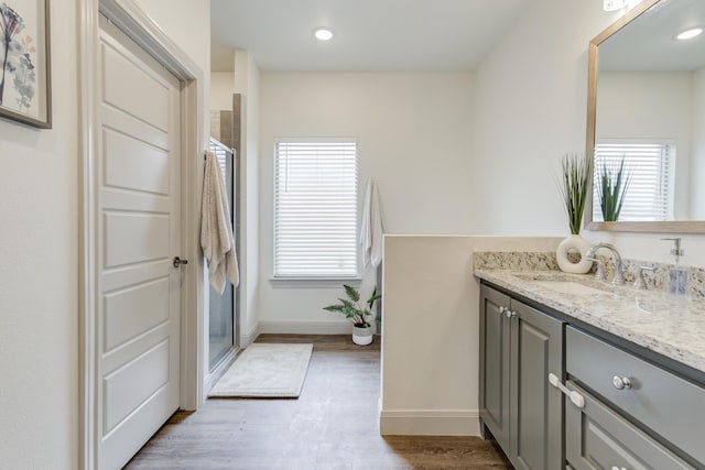 bathroom featuring wood finished floors, vanity, a stall shower, and baseboards