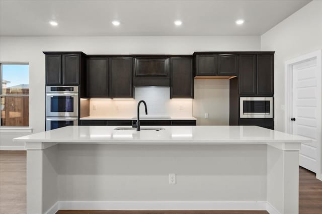 1204 E 31st St, Wolfforth, TX 79382 - kitchen featuring wood-type flooring, sink, backsplash, a kitchen island with sink, and stainless steel appliances