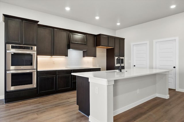 1204 E 31st St, Wolfforth, TX 79382 - kitchen with hardwood / wood-style floors, sink, a center island with sink, and stainless steel double oven