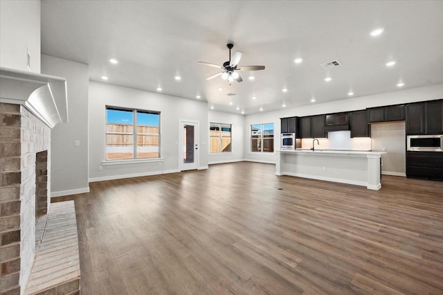 1204 E 31st St, Wolfforth, TX 79382 - unfurnished living room featuring a brick fireplace, dark wood-type flooring, sink, and ceiling fan