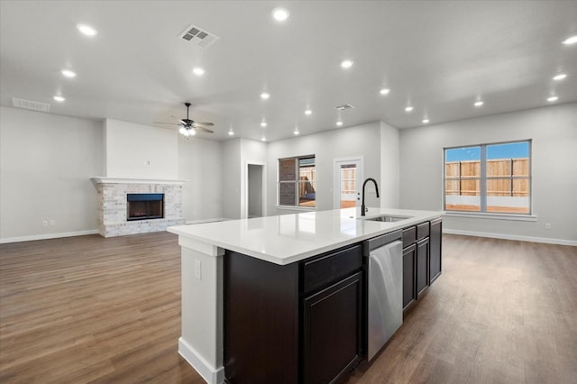 1204 E 31st St, Wolfforth, TX 79382 - kitchen with sink, dishwasher, wood-type flooring, a center island with sink, and a brick fireplace
