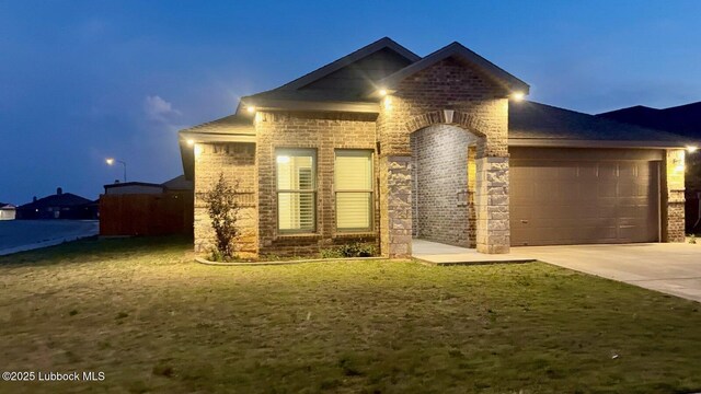 7501 100th St, Lubbock, TX 79424 - view of front facade with brick siding, an attached garage, driveway, and a front yard
