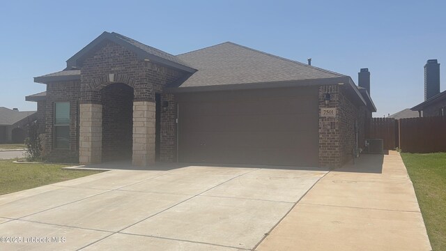 7501 100th St, Lubbock, TX 79424 - french country style house with brick siding, an attached garage, concrete driveway, and roof with shingles