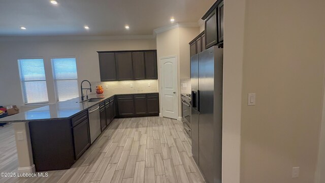 7501 100th St, Lubbock, TX 79424 - kitchen with appliances with stainless steel finishes, tasteful backsplash, a peninsula, ornamental molding, and light wood-style floors