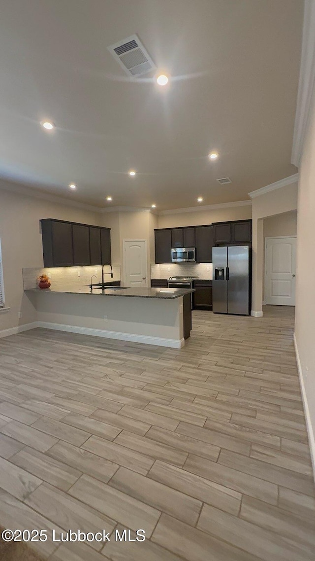 7501 100th St, Lubbock, TX 79424 - kitchen with stainless steel appliances, ornamental molding, recessed lighting, light wood finished floors, and dark cabinetry