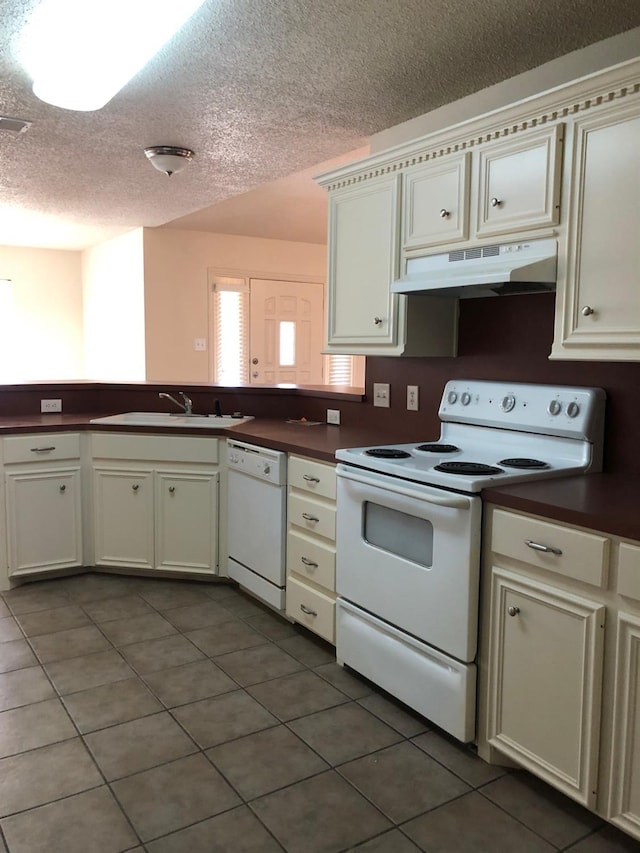 kitchen featuring dark tile patterned floors, sink, a textured ceiling, and white appliances