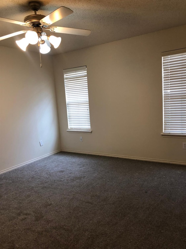 unfurnished room with dark colored carpet, ceiling fan, and a textured ceiling