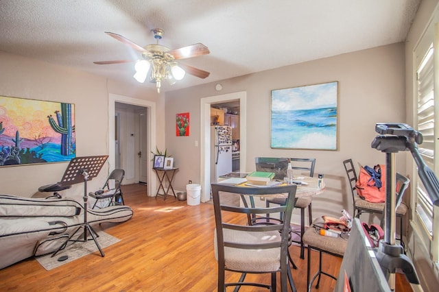 dining room with ceiling fan, a textured ceiling, and light wood-type flooring