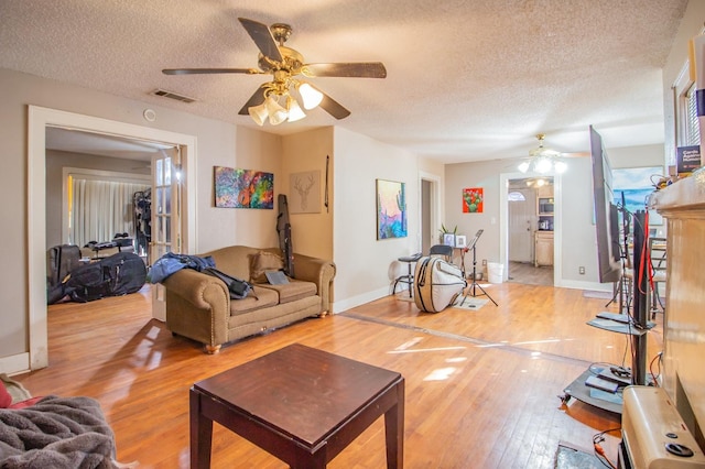 living room featuring ceiling fan, wood-type flooring, and a textured ceiling