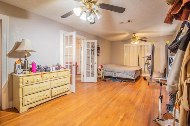 bedroom featuring french doors, ceiling fan, light hardwood / wood-style flooring, and a textured ceiling