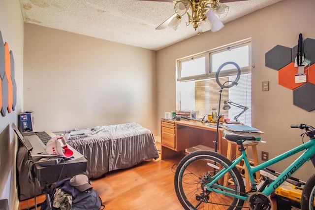 bedroom with wood-type flooring, ceiling fan, and a textured ceiling