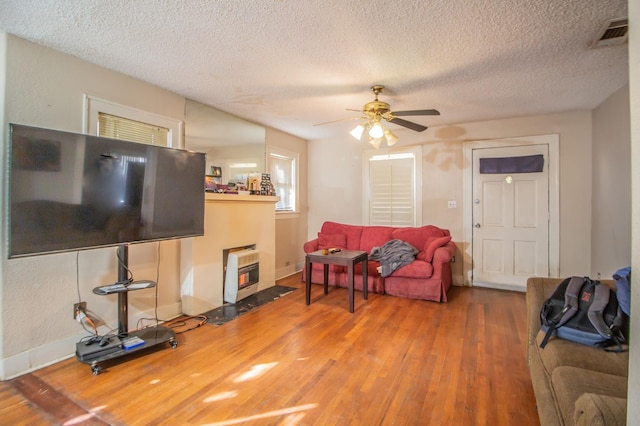 living room featuring heating unit, hardwood / wood-style flooring, a textured ceiling, and ceiling fan