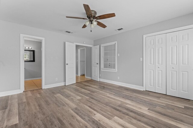 unfurnished bedroom with connected bathroom, light hardwood / wood-style flooring, a closet, and ceiling fan