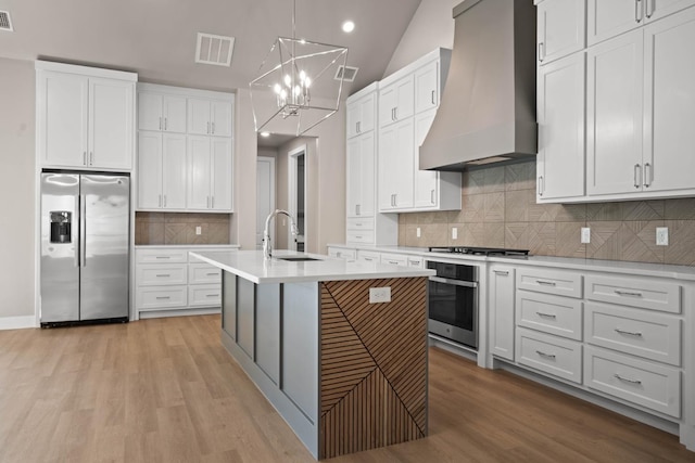 kitchen featuring stainless steel appliances, custom range hood, and white cabinets