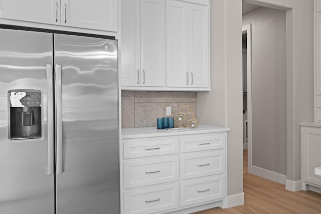 kitchen with stainless steel refrigerator with ice dispenser, light wood-type flooring, tasteful backsplash, and white cabinets