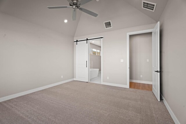 unfurnished bedroom with connected bathroom, high vaulted ceiling, light colored carpet, ceiling fan, and a barn door