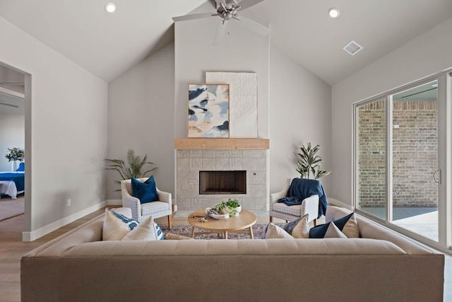 living room featuring hardwood / wood-style flooring, a tile fireplace, vaulted ceiling, and ceiling fan