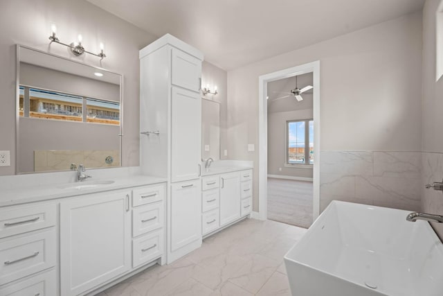 bathroom featuring ceiling fan, a tub to relax in, and vanity