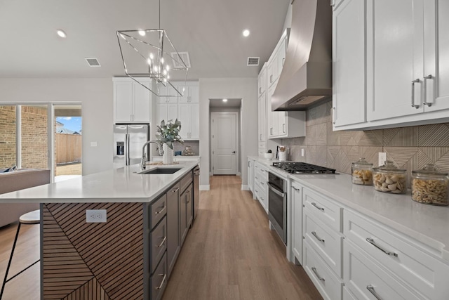 kitchen with white cabinetry, premium range hood, a kitchen bar, and stainless steel appliances