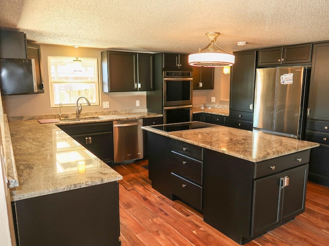 kitchen featuring a kitchen island, appliances with stainless steel finishes, sink, and decorative light fixtures