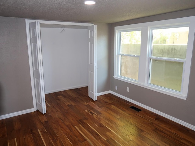 unfurnished bedroom with dark wood-type flooring, a closet, and a textured ceiling