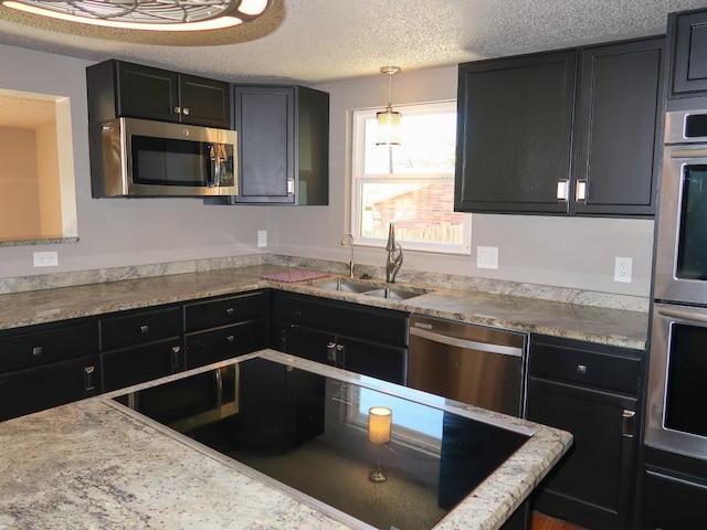 kitchen featuring pendant lighting, sink, stainless steel appliances, and a textured ceiling