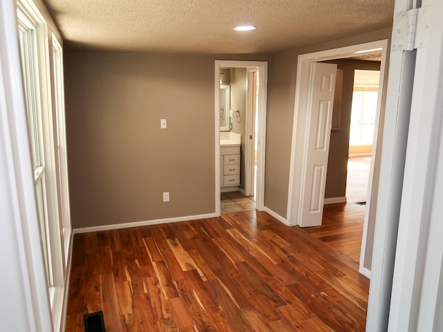 unfurnished bedroom featuring dark hardwood / wood-style flooring, ensuite bath, and a textured ceiling