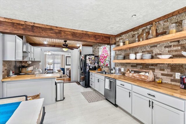 spare room featuring ceiling fan, wooden walls, a textured ceiling, and a skylight