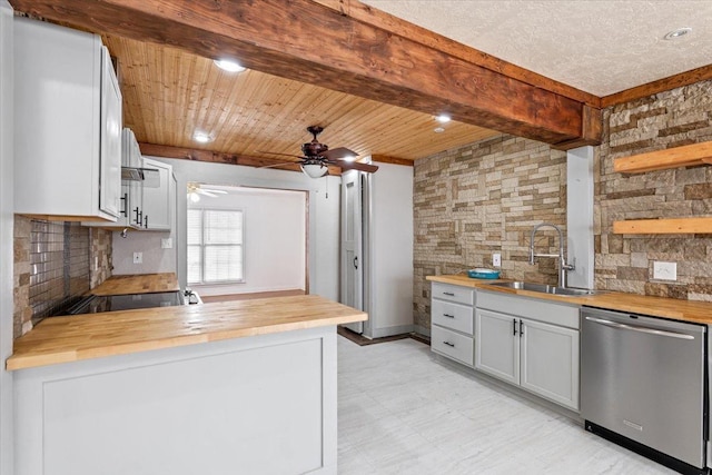 kitchen featuring butcher block countertops, white cabinetry, sink, backsplash, and stainless steel dishwasher