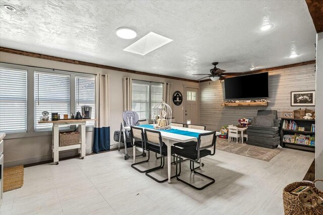 kitchen with ceiling fan, wall chimney exhaust hood, wood counters, a barn door, and beamed ceiling