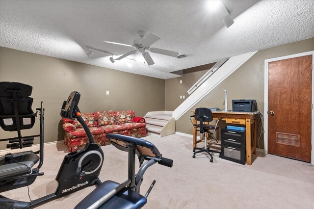 exercise room with ceiling fan, light colored carpet, rail lighting, and a textured ceiling