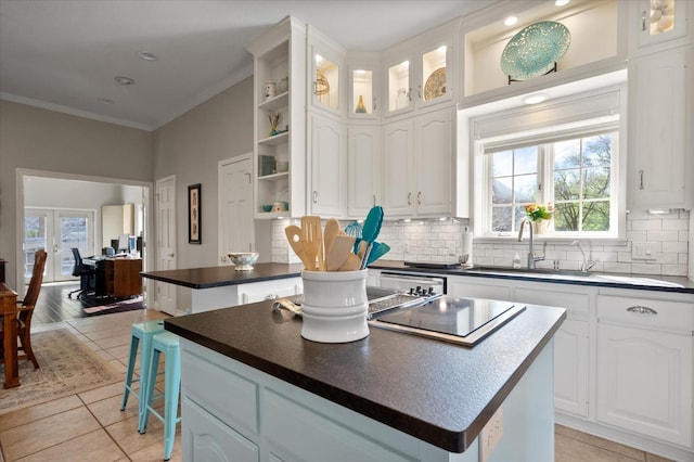 kitchen with white cabinetry, sink, decorative backsplash, a center island, and crown molding