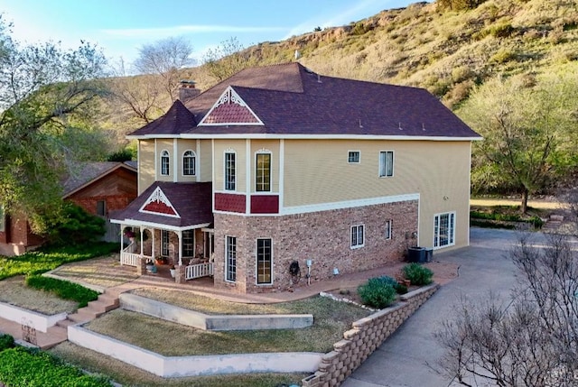 rear view of property featuring a mountain view, covered porch, and central air condition unit