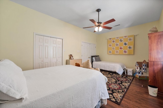 bedroom with multiple closets, ceiling fan, and dark hardwood / wood-style flooring