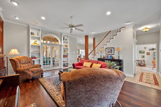 living room featuring built in shelves, ceiling fan, wood-type flooring, and crown molding