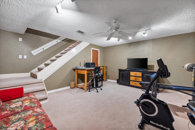 carpeted home office with ceiling fan, track lighting, and a textured ceiling