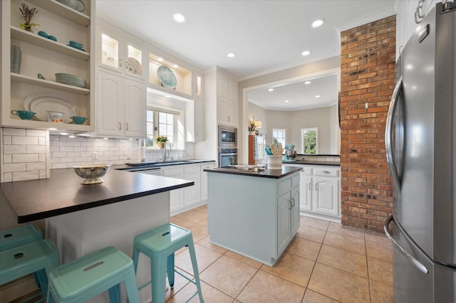 kitchen featuring a breakfast bar area, white cabinetry, a center island, appliances with stainless steel finishes, and backsplash