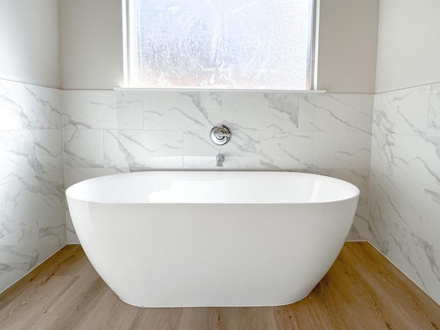 bathroom with a tub to relax in and wood-type flooring