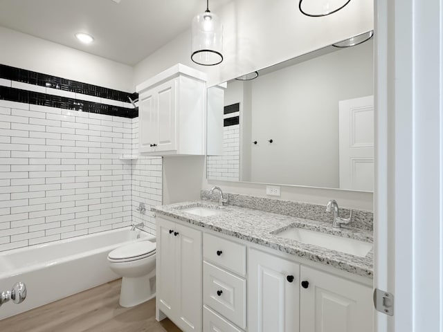 full bathroom featuring hardwood / wood-style flooring, tiled shower / bath, vanity, and toilet