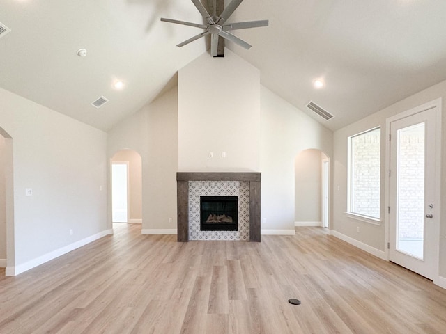 unfurnished living room featuring visible vents, arched walkways, and a tile fireplace