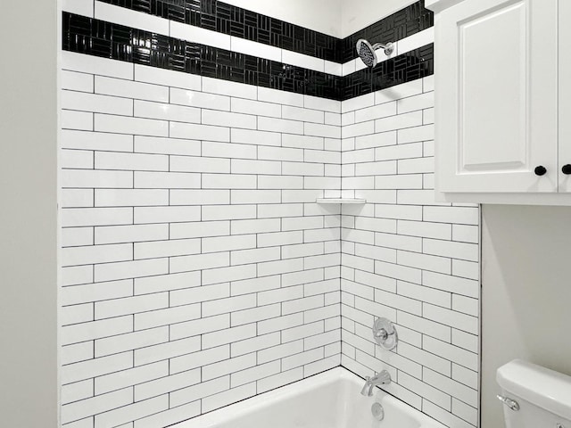 bathroom featuring tiled shower / bath combo and toilet