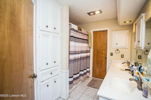 5008 59th St, Lubbock, TX 79414 - bathroom with double vanity, tile patterned flooring, curtained shower, and a textured ceiling