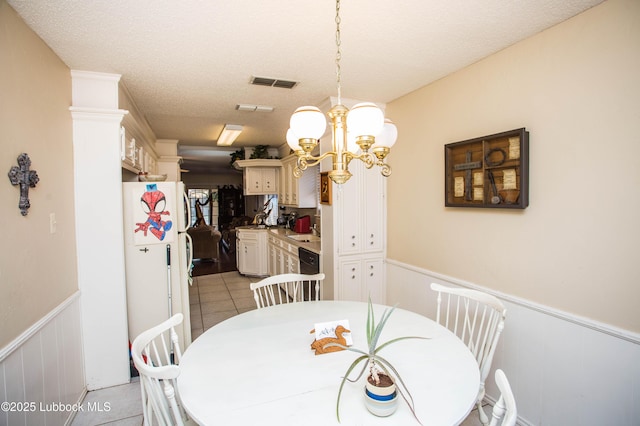 5008 59th St, Lubbock, TX 79414 - dining area with a wainscoted wall, light tile patterned floors, a textured ceiling, and a decorative wall