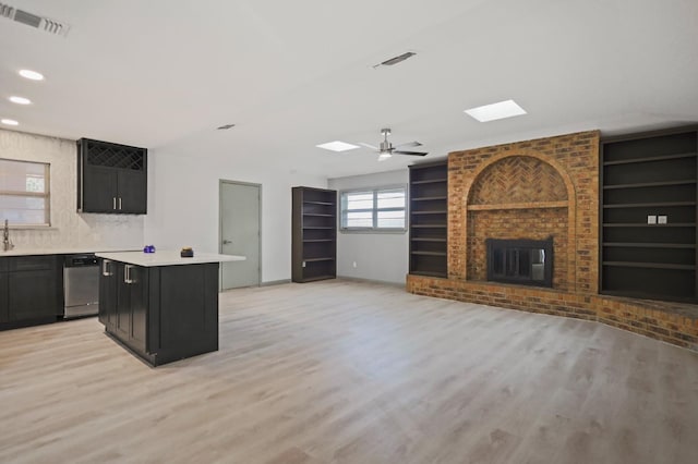 kitchen with a brick fireplace, built in features, dishwasher, and a kitchen island