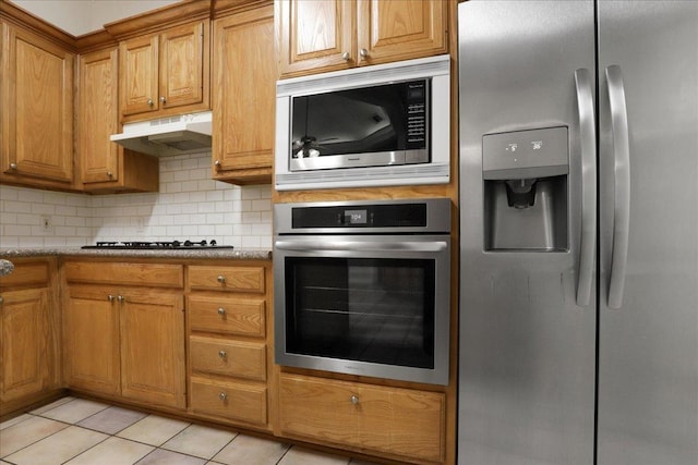 kitchen featuring stainless steel appliances, tasteful backsplash, light tile patterned floors, and light stone counters