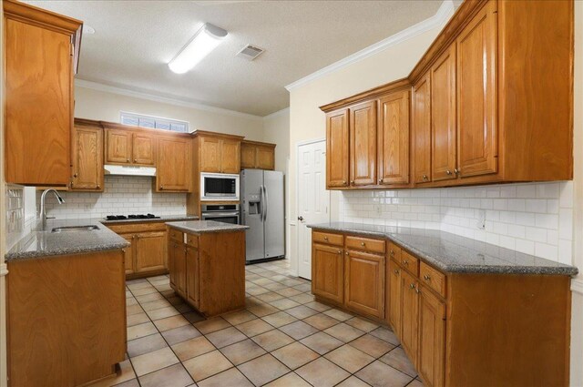 kitchen with sink, appliances with stainless steel finishes, backsplash, a center island, and a textured ceiling